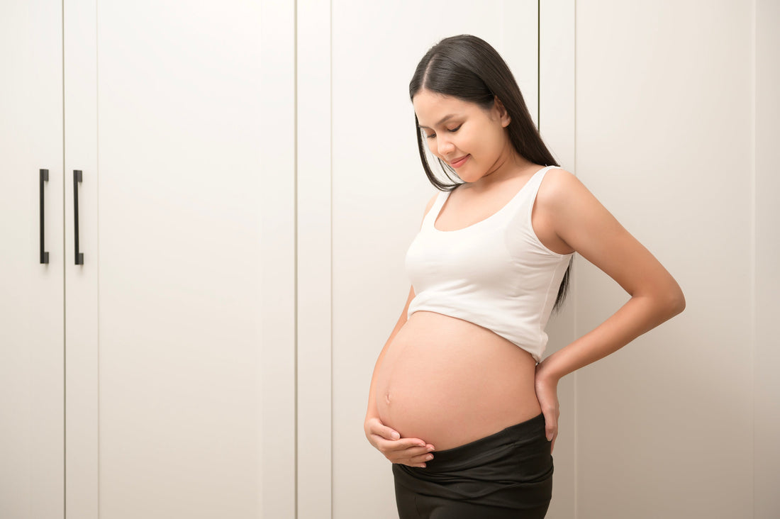 Pregnant woman smiling and holding belly illustrating timing intercourse for conception success